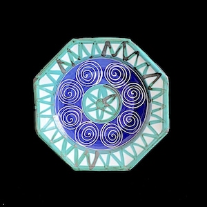 May include: Octagonal ceramic plate with a blue and white design. The center of the plate features a stylized bird with a green and white design. The plate is surrounded by a border of blue and white spirals.