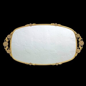 May include: A gold-colored serving tray with a white interior and a decorative floral design around the edge.