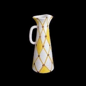 May include: A white ceramic pitcher with a yellow and brown diamond pattern. The pitcher has a wide mouth and a handle.