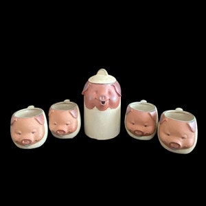 May include: A set of five ceramic pig-shaped mugs, including a larger pitcher. The mugs are beige with brown pig faces and snouts.