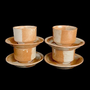 May include: Set of four ceramic coffee cups and saucers with a brown and white speckled glaze. The cups and saucers are stacked in pairs.