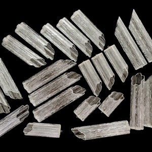 May include: A collection of clear glass tubes with a textured surface. The tubes are arranged in a random pattern on a black background.