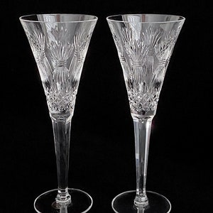 K&ouml;nnte beinhalten: Zwei klare Kristall-Champagnerfl&ouml;ten mit einem geschliffenen Glasdesign. Die Fl&ouml;ten haben einen hohen, schlanken Stiel und eine breite, schalenf&ouml;rmige Oberseite.