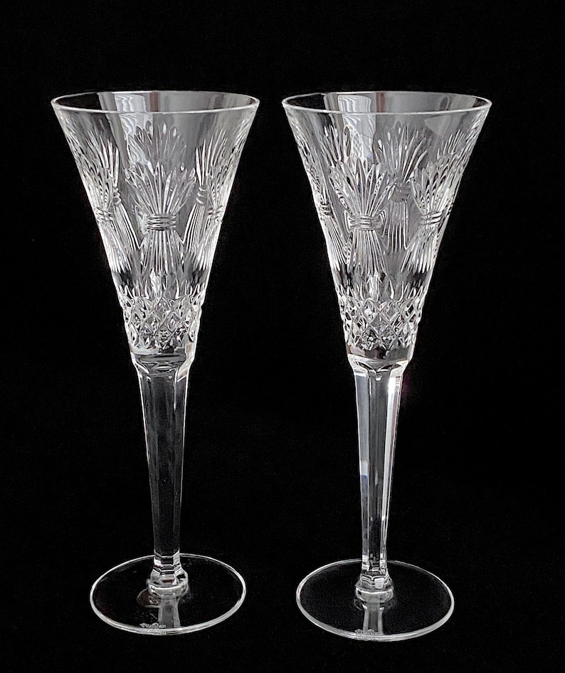 K&ouml;nnte beinhalten: Zwei klare Kristall-Champagnerfl&ouml;ten mit einem geschliffenen Glasdesign. Die Fl&ouml;ten haben einen hohen, schlanken Stiel und eine breite, schalenf&ouml;rmige Oberseite.