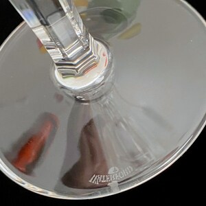 K&ouml;nnte beinhalten: Nahaufnahme des Bodens eines klaren Weinglases aus Glas mit einem dicken Stiel. Das Glas hat einen klaren, runden Boden mit dem Wort "Lalique" in den Boden ge&auml;tzt.
