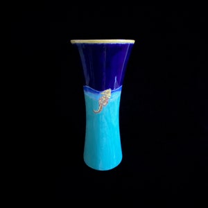 May include: A blue and turquoise ceramic vase with a yellow rim and a seahorse design.