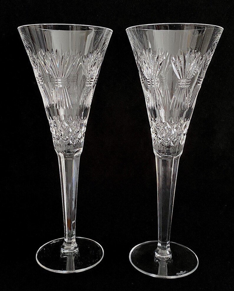 K&ouml;nnte beinhalten: Zwei klare Champagnerfl&ouml;ten aus Glas mit geschliffenem Kristallmuster. Die Fl&ouml;ten haben einen hohen, schlanken Stiel und eine breite, schalenf&ouml;rmige Oberseite.