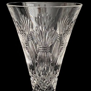 K&ouml;nnte beinhalten: Eine klare Kristall-Champagnerfl&ouml;te mit einem detaillierten, ge&auml;tzten Design aus Weizen&auml;hren. Die Fl&ouml;te hat einen breiten Kelch und einen langen Stiel.