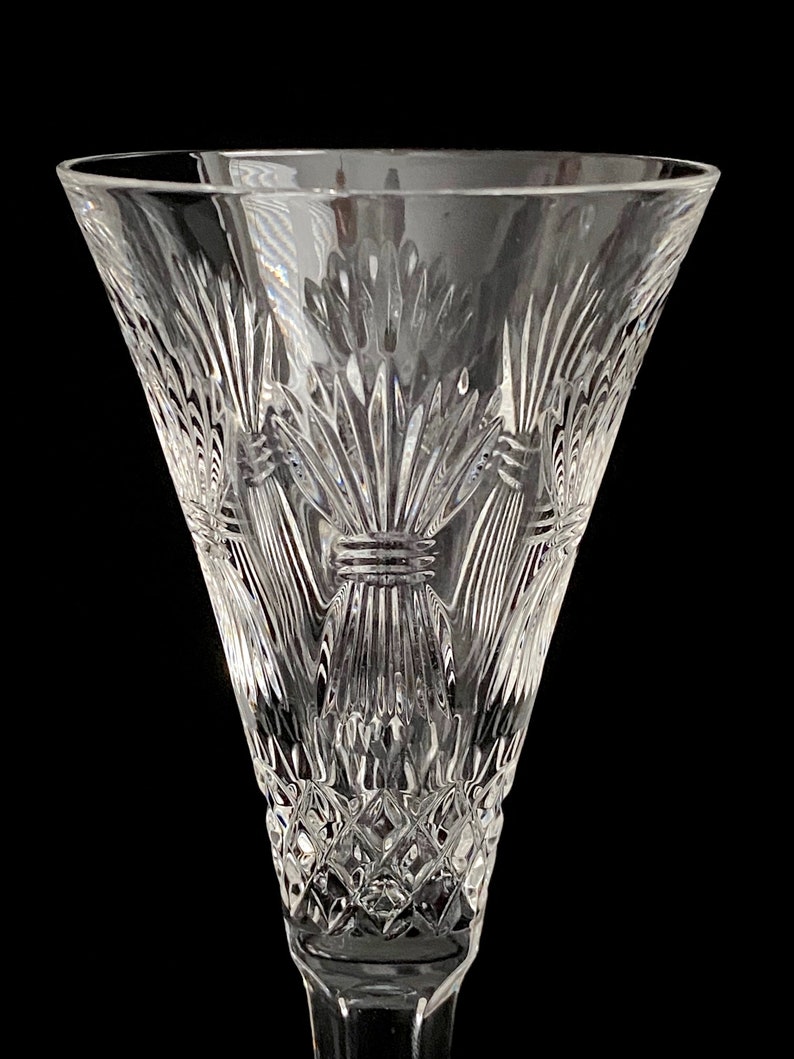 K&ouml;nnte beinhalten: Eine klare Kristall-Champagnerfl&ouml;te mit einem detaillierten, ge&auml;tzten Design aus Weizen&auml;hren. Die Fl&ouml;te hat einen breiten Kelch und einen langen Stiel.