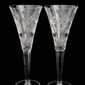 K&ouml;nnte beinhalten: Zwei klare Kristall-Champagnerfl&ouml;ten mit einem geschliffenen Glasdesign. Die Fl&ouml;ten haben einen hohen, schlanken Stiel und eine breite, runde Schale.