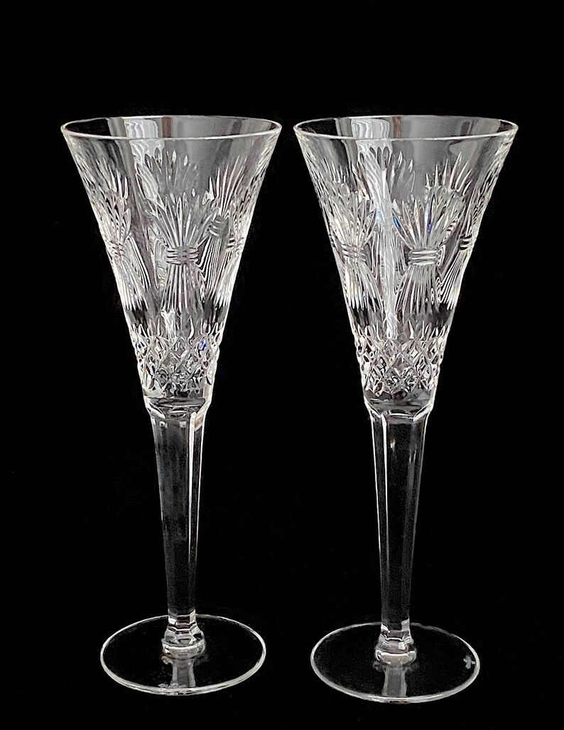 K&ouml;nnte beinhalten: Zwei klare Kristall-Champagnerfl&ouml;ten mit einem geschliffenen Glasdesign. Die Fl&ouml;ten haben einen hohen, schlanken Stiel und eine breite, runde Schale.
