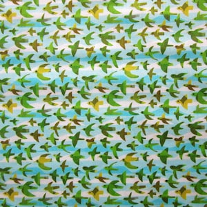 Könnte beinhalten: Ein blauer und weißer Stoff mit einem sich wiederholenden Muster aus grünen Vögeln, die diagonal fliegen.