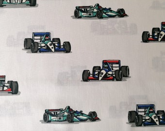 May include: A white fabric with a repeating pattern of blue, red, and green race cars. The cars have the number "12" on them.