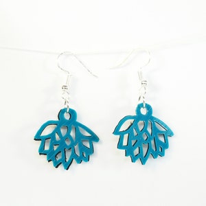 May include: A pair of teal earrings with a leaf design. The earrings have a layered appearance with a black backing and silver ear wires. They are suspended against a white backdrop.