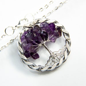 May include: A silver necklace with a wire-wrapped tree of life pendant featuring amethyst gemstones. The pendant is circular and has a braided wire design around the edge.