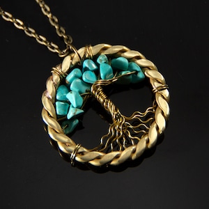 Pode incluir: Um colar de ouro com um pingente de árvore da vida de pedra turquesa. O pingente é feito de fio enrolado em torno das pedras e tem uma corrente de corda trançada.