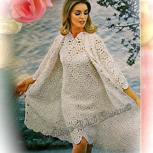 May include: A vintage crochet dress and matching jacket in white. The dress is knee-length with a scalloped hem, and the jacket has three-quarter sleeves. The design features floral patterns. The image has a soft, vintage aesthetic.