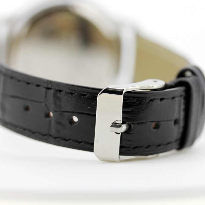 Pode incluir: Uma pulseira de rel&oacute;gio de couro preto com uma fivela prateada. A pulseira tem um padr&atilde;o de crocodilo.