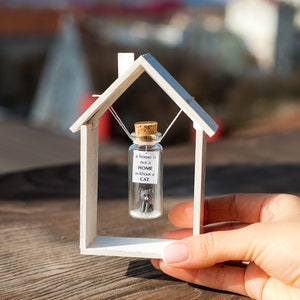 a miniature house with a tiny cat inside of it