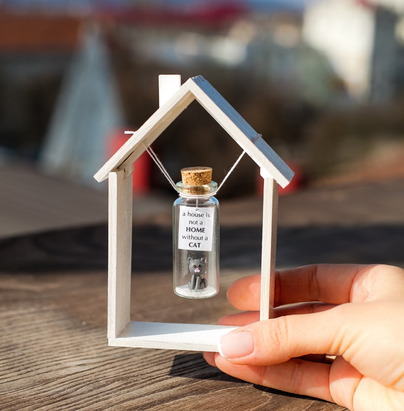 a miniature house with a tiny cat inside of it