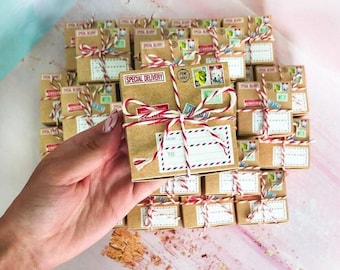 May include: A collection of small square cardboard gift boxes wrapped in red and white baker's twine. Each box features printed postage stamps, a 'SPECIAL DELIVERY' label, and a 'FROM' and 'TO' address field with red and blue striped borders.