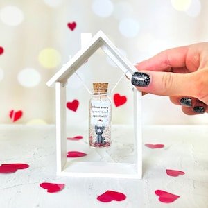 a person holding a tiny house shaped bottle