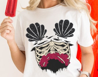May include: White t-shirt featuring a skeleton design with a cosmic shell-like pattern and a red floral element. The word "WHITE" is printed at the bottom. The person is holding a red popsicle.