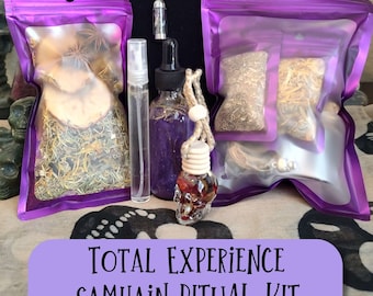 May include: A Samhain ritual kit with various components, including purple pouches filled with herbs and spices, a small spray bottle, a dropper bottle, and a skull-shaped car air freshener. The kit also includes a pendant necklace. The text "TOTAL EXPERIENCE SAMHAIN RITUAL KIT" is displayed.