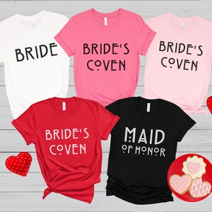 May include: Five t-shirts with different text printed on them. The shirts are white, pink, red, and black. The text on the shirts reads "Bride", "Bride's Coven", "Maid of Honor", and "Bride's Coven".