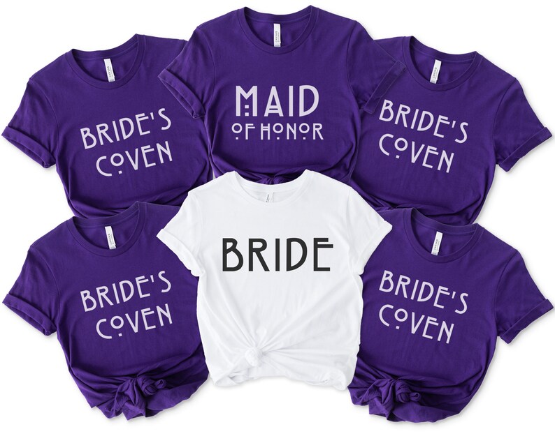 May include: Five purple t-shirts with white text that reads "Bride's Coven" and one white t-shirt with black text that reads "Bride". One purple t-shirt has white text that reads "Maid of Honor".