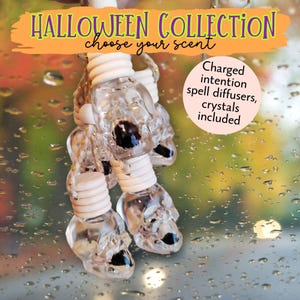 May include: Clear skull-shaped spell diffusers with white tops and black accents, part of a Halloween Collection. The image includes text that reads "Halloween Collection choose your scent" and "Charged intention spell diffusers, crystals included."