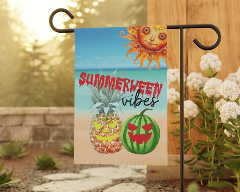May include: A garden flag with a summer and Halloween theme. It features a smiling sun, a pineapple with a jack-o-lantern face, a watermelon with a jack-o-lantern face, and the text "Summerween vibes".
