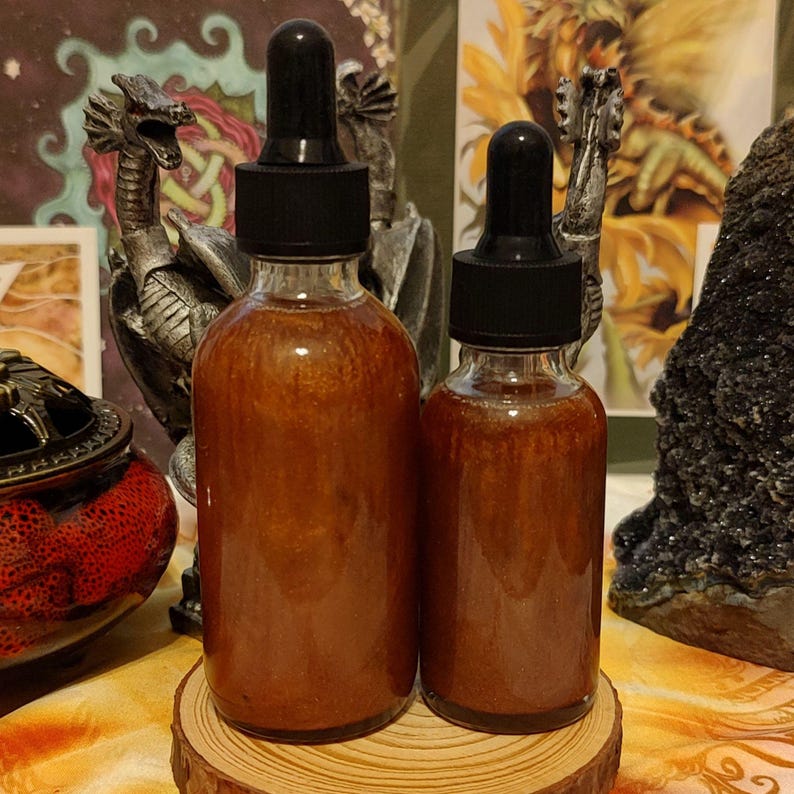 Peut inclure: Deux flacons en verre ambr&eacute; avec des compte-gouttes, remplis d'un liquide orange chatoyant. Les flacons sont pos&eacute;s sur une surface en bois.