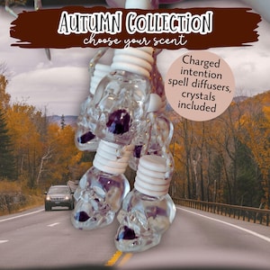 May include: Clear skull-shaped spell diffusers with white tops and purple accents. The text "Autumn Collection choose your scent" is displayed above the diffusers. The image also includes the text "Charged intention spell diffusers, crystals included."