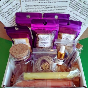 May include: A ritual kit with various components, including a glass jar with a cork, small bags of herbs, a bottle of oil, candles, and a bundle of twine with a sun charm. The kit includes instructions for use.