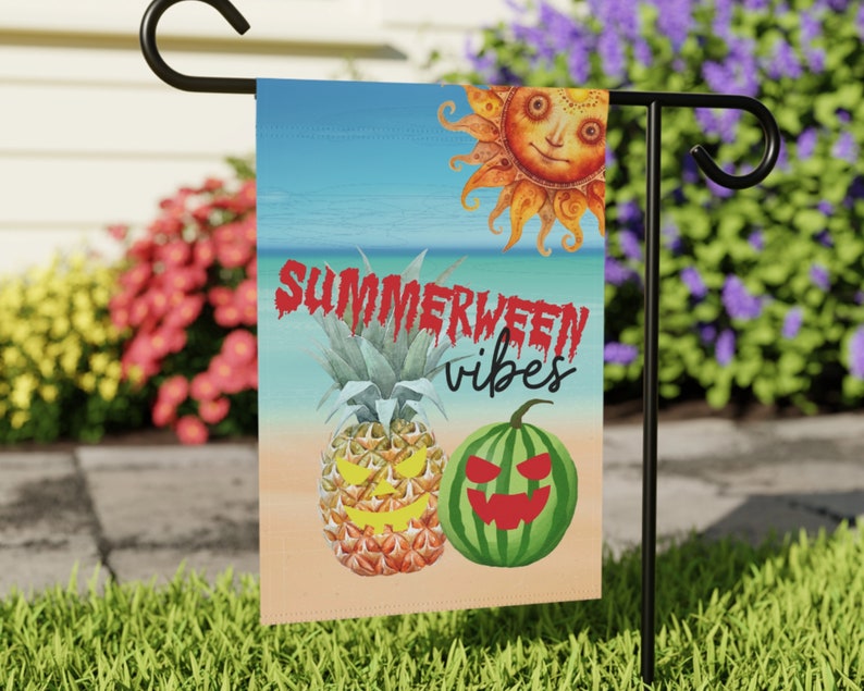 May include: A summer-themed garden flag with a pineapple, watermelon, and sun design. The text on the flag reads "Summerween vibes".