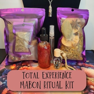 May include: A Mabon ritual kit with various components, including sealed bags of herbs, a dropper bottle, a spray bottle, and a skull-shaped vial. The kit also includes a necklace with a pendant. The text "TOTAL EXPERIENCE MABON RITUAL KIT" is displayed.