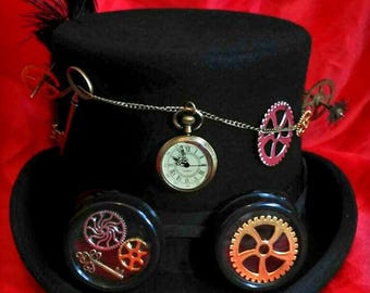 Peut inclure: Haut-de-forme noir avec lunettes steampunk et engrenages décoratifs. Une montre de poche est suspendue à une chaîne à l'avant. Une plume noire et des engrenages supplémentaires ornent le chapeau, créant une esthétique vintage unique.