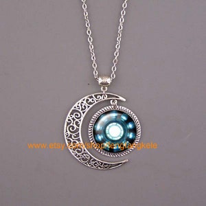 Może przedstawiać: Srebrny naszyjnik z zawieszką w kształcie półksiężyca i okrągłym szklanym kameą przedstawiającym niebiesko-biały wzór Iron Mana.