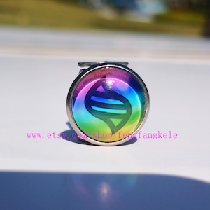 May include: A round, silver-toned ring with a colorful, rainbow-gradient design. The ring features a central emblem with a blue and green design. The text "www.etsy.com/shop/fengfangkele" is printed at the bottom.