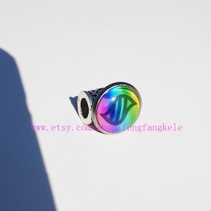 May include: A silver ring with a large, round, iridescent stone. The stone has a rainbow gradient and a stylized green and blue design. The text "www.etsy.com/shop/fengfangkele" is printed in pink.