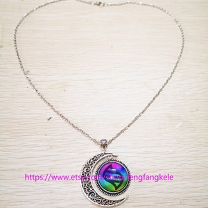 Op de afbeelding: Een zilveren ketting met een halve maan hanger. De hanger heeft een kleurrijk, rond glazen ontwerp met een swirl-patroon. De tekst "https://www.etsy.com/shop/mengfangkele" is zichtbaar onderaan de afbeelding.