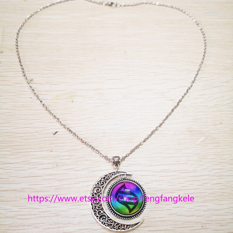 Op de afbeelding: Een zilveren ketting met een halve maan hanger. De hanger heeft een kleurrijk, rond glazen ontwerp met een swirl-patroon. De tekst "https://www.etsy.com/shop/mengfangkele" is zichtbaar onderaan de afbeelding.