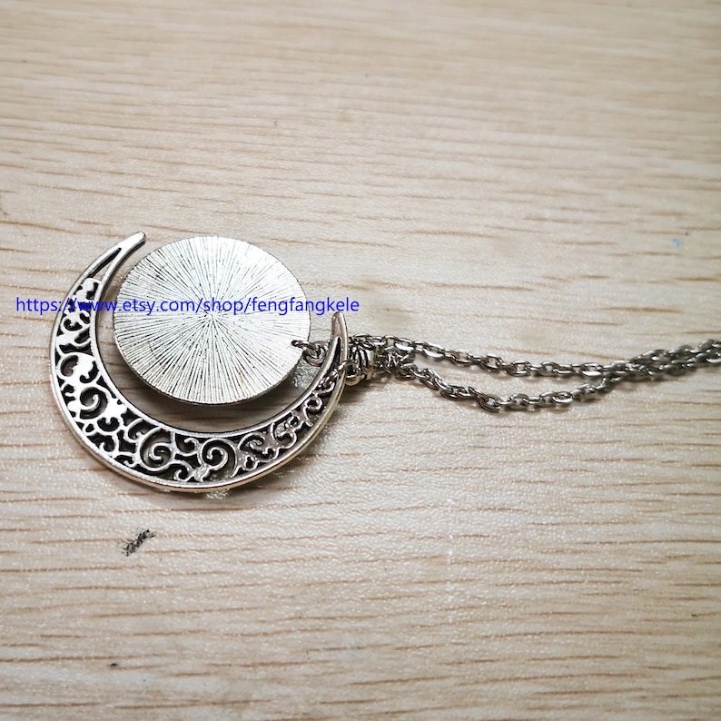 Op de afbeelding: Zilveren halve maan ketting met een ronde hanger. De hanger heeft een getextureerd oppervlak en is met een zilveren ring aan de ketting bevestigd.