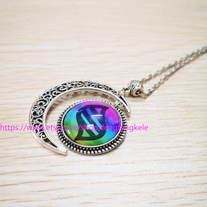 Op de afbeelding: Een zilveren halve maan ketting met een regenboogkleurige glazen hanger met een DNA-symbool. De hanger is omgeven door een zilveren rand.