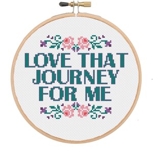 Può includere: Un cerchio da ricamo bianco con un motivo floreale turchese e viola e il testo "LOVE THAT JOURNEY FOR ME".