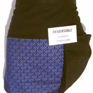 May include: Reversible black apron with a blue and black fan-shaped pattern on the front pocket. The apron has three pockets on both sides. The apron is made of a durable fabric.
