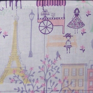 May include: A white fabric with a purple and pink floral pattern. The fabric features a pink Eiffel Tower, a purple street lamp, a pink and white striped awning, a pink and white food cart, a purple bench, and a purple bird.