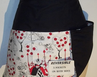 Puede incluir: Delantal reversible negro y blanco con estampado rojo y blanco de Alicia en el País de las Maravillas. El delantal tiene tres bolsillos a cada lado y dice "REVERSIBLE 3 POCKETS ON BOTH SIDES".