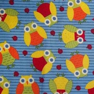 May include: A blue and white striped fabric with a repeating pattern of colorful owls and ladybugs. The owls have yellow, red, and green accents. The ladybugs are red with black spots.